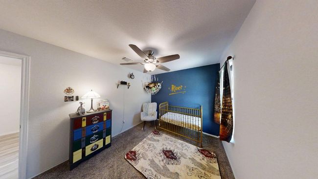 Carpeted bedroom with a nursery area and ceiling fan | Image 11