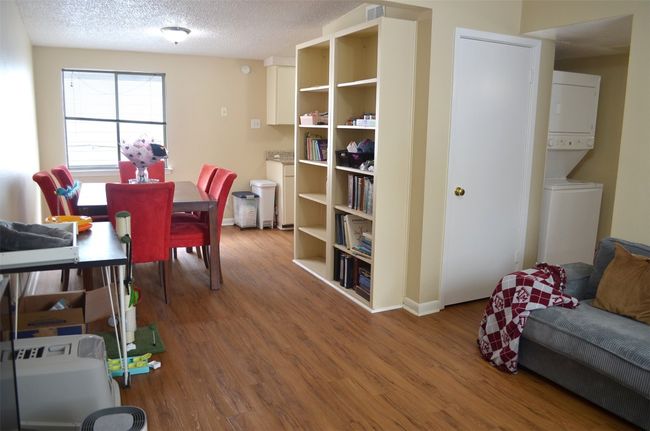 Dining area with stacked washing machine and dryer, wood finished floors, and a textured ceiling | Image 4