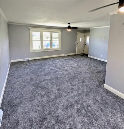 Spare room with crown molding, a textured ceiling, dark carpet, and ceiling fan | Image 3