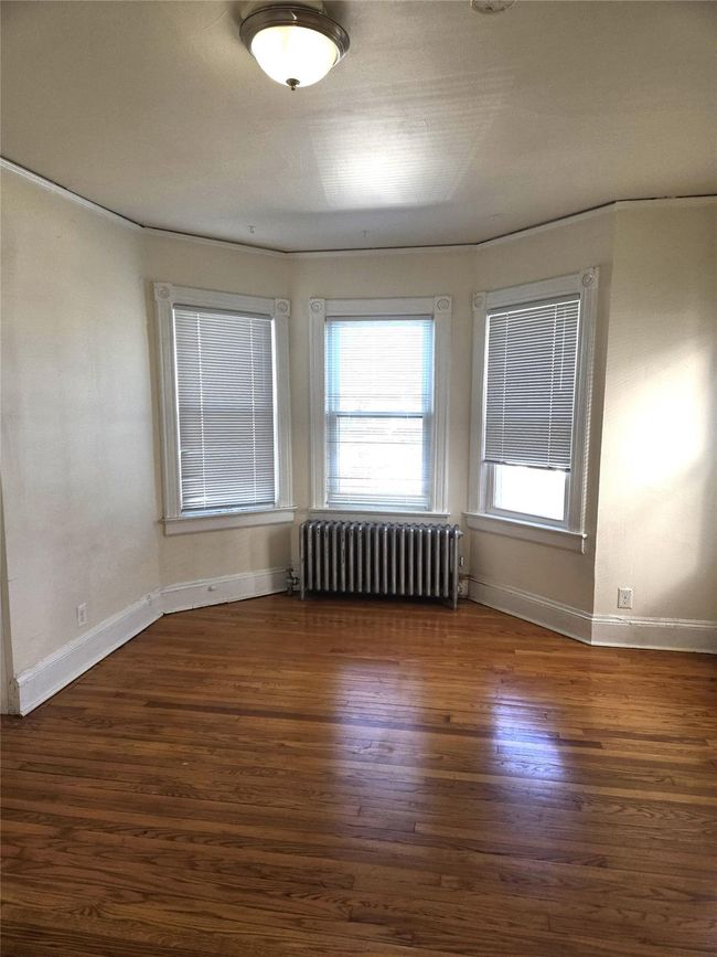 Spare room featuring radiator heating unit, wood finished floors, and baseboards | Image 10