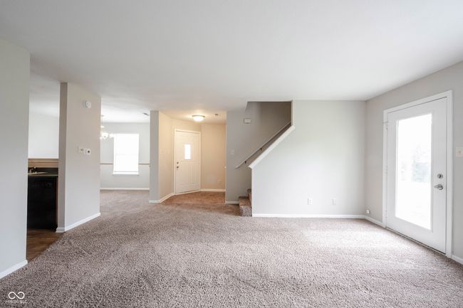 unfurnished living room with carpet, baseboards, and stairway | Image 8