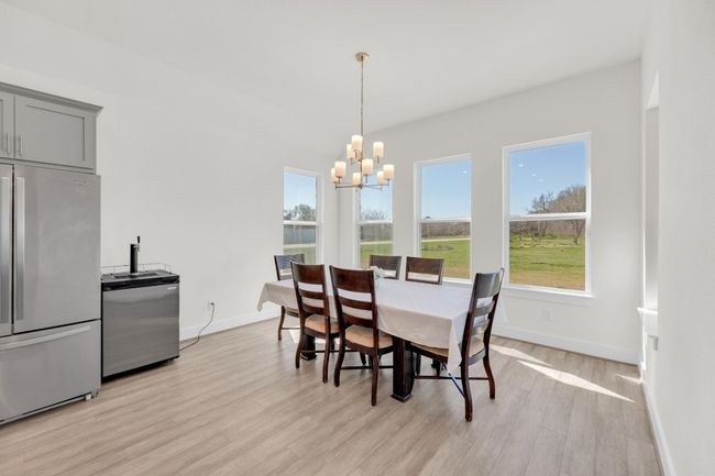 Dining room with light wood-type flooring, an inviting chandelier, and baseboards | Image 15
