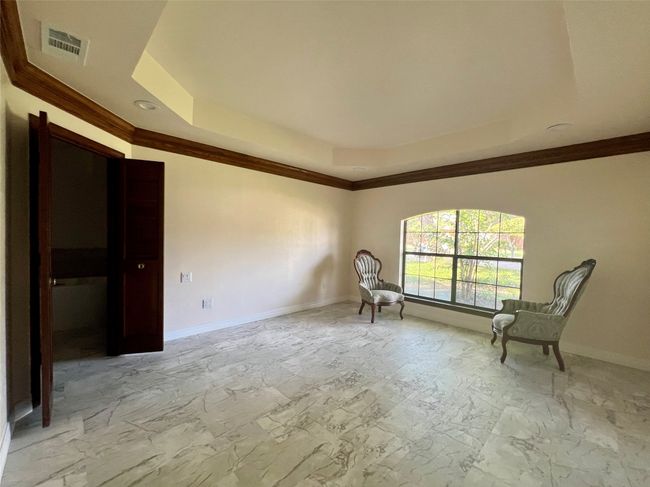 Unfurnished room with a raised ceiling, light marble finish floors, and crown molding | Image 10