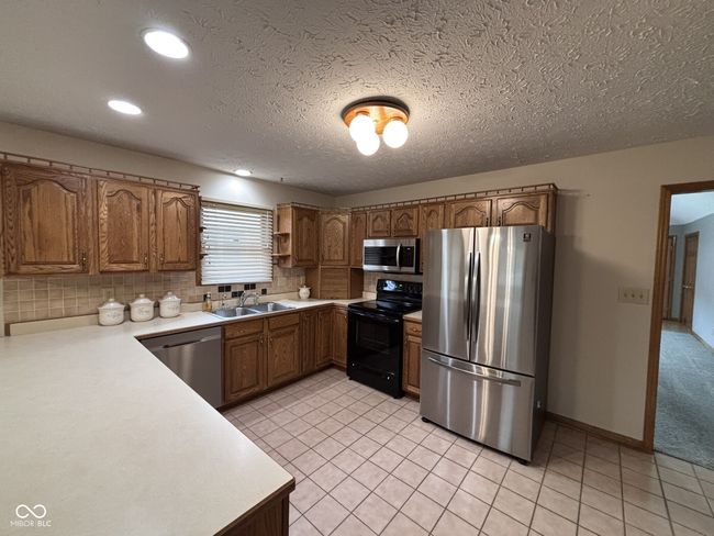 kitchen featuring a sink, light countertops, brown cabinets, and appliances with stainless steel finishes | Image 8