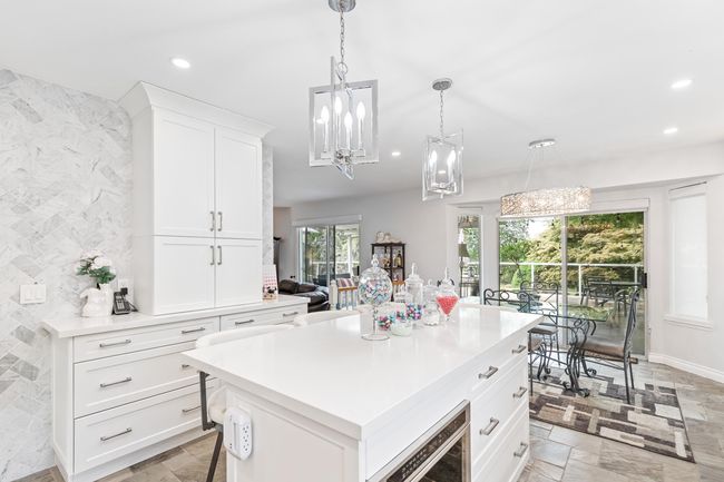 Kitchen featuring recessed lighting, light countertops, stone tile floors, white cabinets, and a center island | Image 12