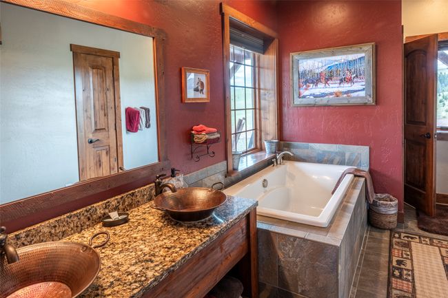 Bathroom featuring a garden tub, a textured wall, double vanity, and tile patterned flooring | Image 45