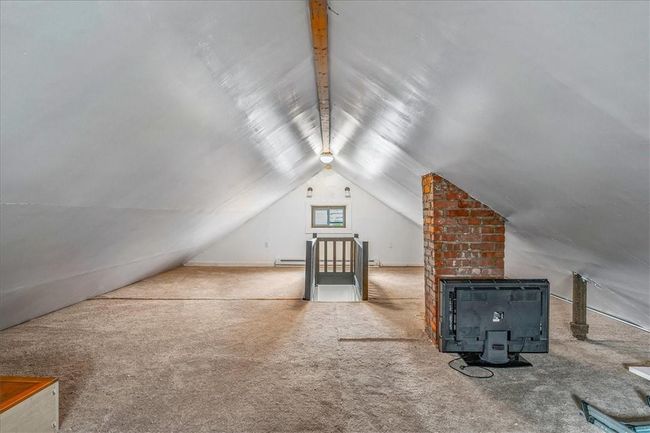 Unit # 70 Additional living space featuring brick wall, a baseboard heating unit, lofted ceiling, and carpet floors | Image 30