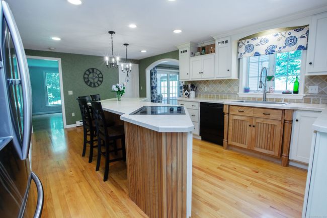 Custom kitchen with custom cabinets, glass cabinets, huge island, cooktop with downdraft exhaust, double ovens, dishwasher and refrigerator, hardwood floors and huge pantry. | Image 8