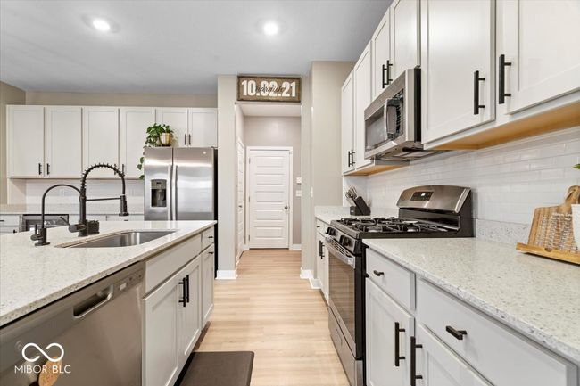 kitchen with appliances with stainless steel finishes, light wood-style flooring, backsplash, light stone countertops, and recessed lighting | Image 13
