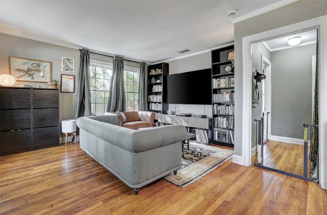 Living area featuring built in shelves, ornamental molding, and wood finished floors | Image 5