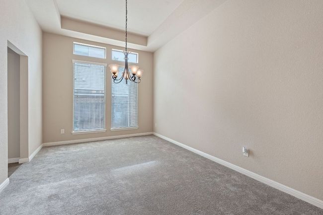 Spare room with a chandelier, carpet flooring, baseboards, and a raised ceiling | Image 11