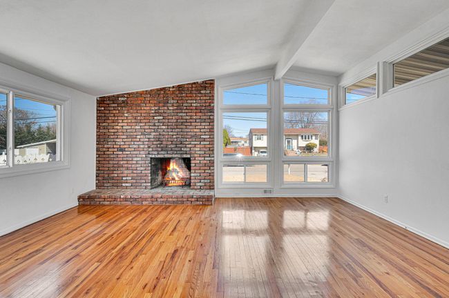 Living room with a brick fireplace, beamed ceiling, and wood-type flooring | Image 4