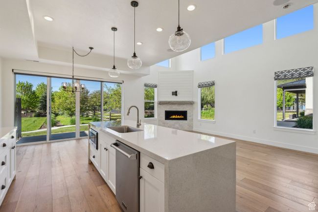 Kitchen featuring a sink, appliances with stainless steel finishes, open floor plan, light wood-style flooring, and white cabinetry | Image 5