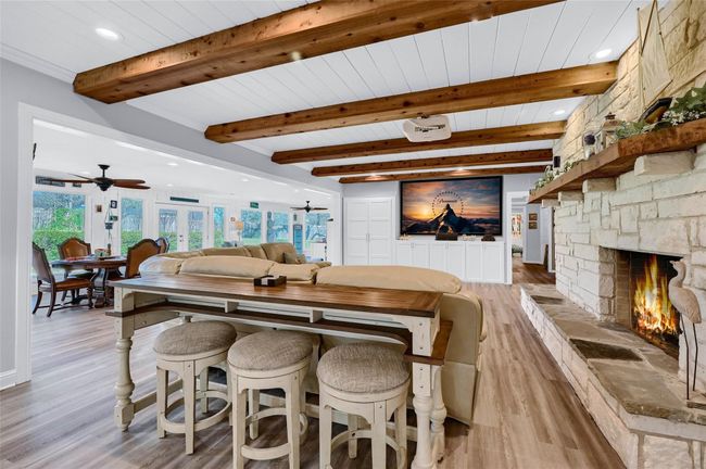 Dining space featuring light wood finished floors, a stone fireplace, ceiling fan, beamed ceiling, and recessed lighting | Image 12