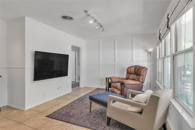 Living room with a textured ceiling, light tile patterned floors, and track lighting | Image 4