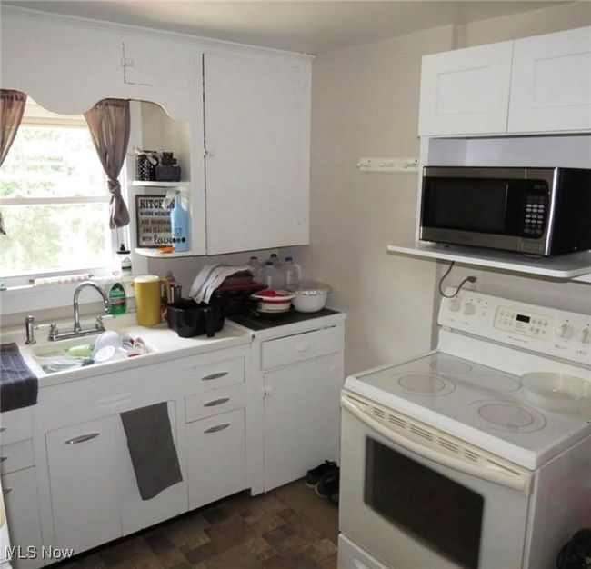 Kitchen featuring white cabinetry, electric range, and sink | Image 4