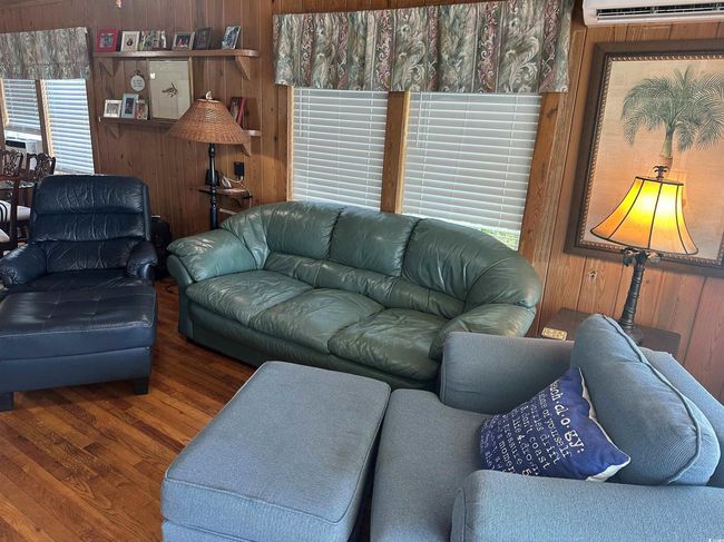 Living room featuring wood walls, wood finished floors, and an AC wall unit | Image 4