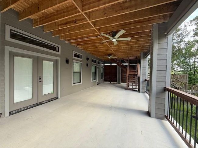 The lower porch comes complete with ceiling fans, large windows, and french doors leading inside to the living room and a single door leading to the primary bedroom. The large porch creates an inviting outdoor living area perfect for relaxation and entertaining. | Image 35