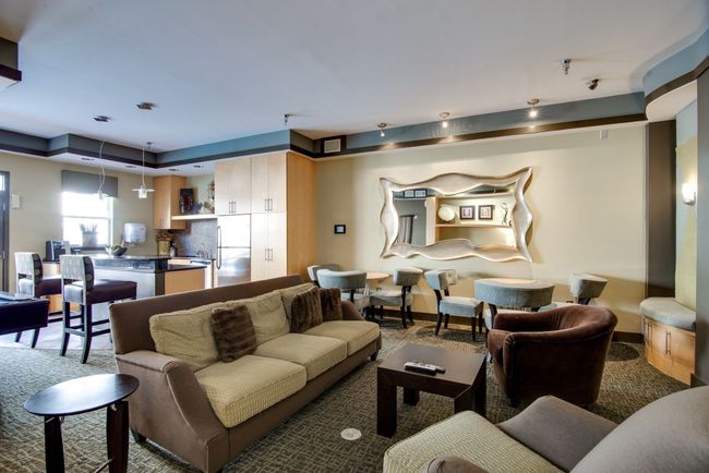 This contemporary common area features comfortable seating, a sleek kitchenette, and modern decor—ideal for casual get-togethers, remote work, or relaxing with neighbors. | Image 26