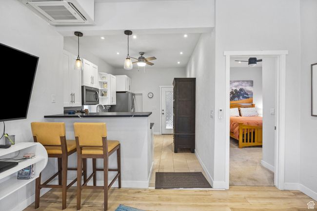 Kitchen featuring light wood-style floors, ceiling fan, white cabinets, dark countertops, and stainless steel appliances | Image 18