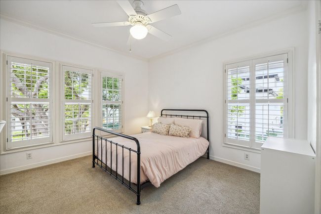 One of the secondary bedrooms with oversized windows with plantation shutters provides abundant natural light. This room features a built-in desk and walk-in closet as well. Hardwood floors that match the rest of the second story are under the carpet!!! | Image 25