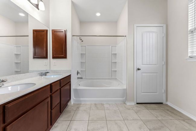 Primary bathroom featuring bathing tub / shower combination, double vanity, and tile patterned flooring | Image 19