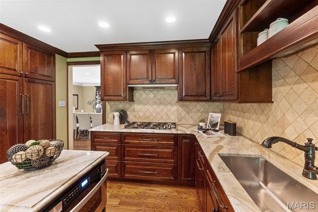 Kitchen featuring ornamental molding, wood finished floors, light stone countertops, backsplash, and recessed lighting | Image 20