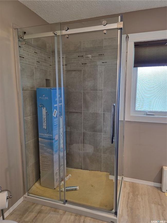 Bathroom with a stall shower, a textured ceiling, wood finished floors, and baseboards | Image 21