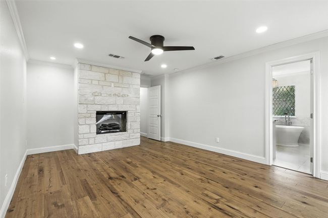 Unfurnished living room with a ceiling fan, ornamental molding, wood-type flooring, a fireplace, and recessed lighting | Image 21