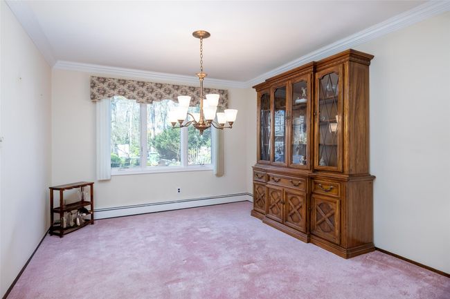 Dining room with ornamental molding, carpet flooring, baseboard heating, and a chandelier | Image 11