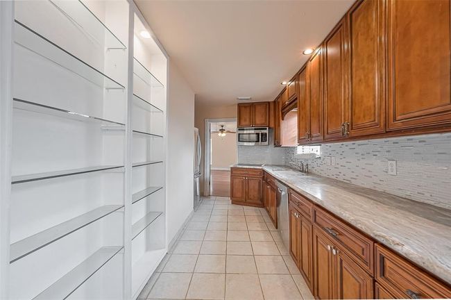 Enjoy added storage and prep space in this extended second kitchen area with a bright window, deep double sink, and upgraded cabinetry. | Image 43