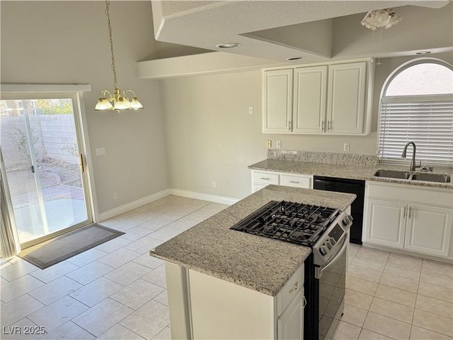 Kitchen with light stone counters, a sink, white cabinets, stainless steel gas range oven, and dishwasher | Image 43