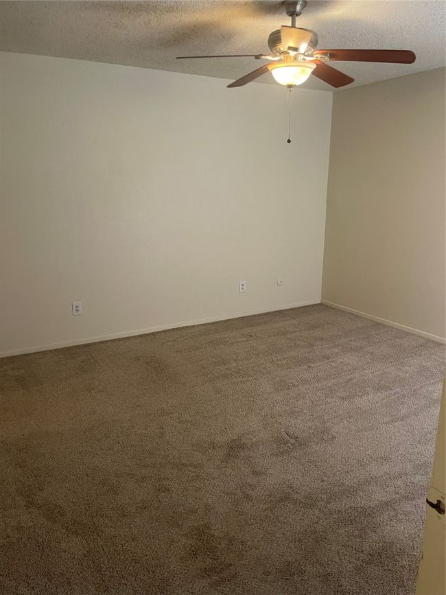Empty room with a textured ceiling, a ceiling fan, and carpet | Image 12