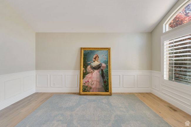 Empty room with wood finished floors, a wainscoted wall, and lofted ceiling | Image 6