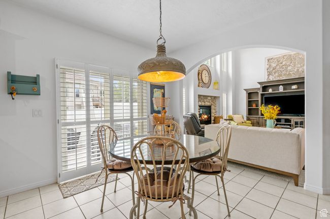Dining space featuring arched walkways, baseboards, a stone fireplace, and light tile patterned floors | Image 18