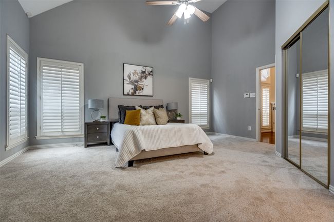 Carpeted bedroom featuring high vaulted ceiling, baseboards, multiple windows, and a closet | Image 14