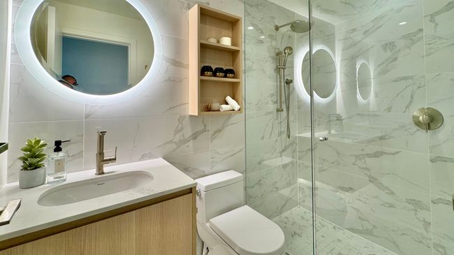 Full bathroom featuring tile walls, toilet, vanity, and a marble finish shower | Image 11