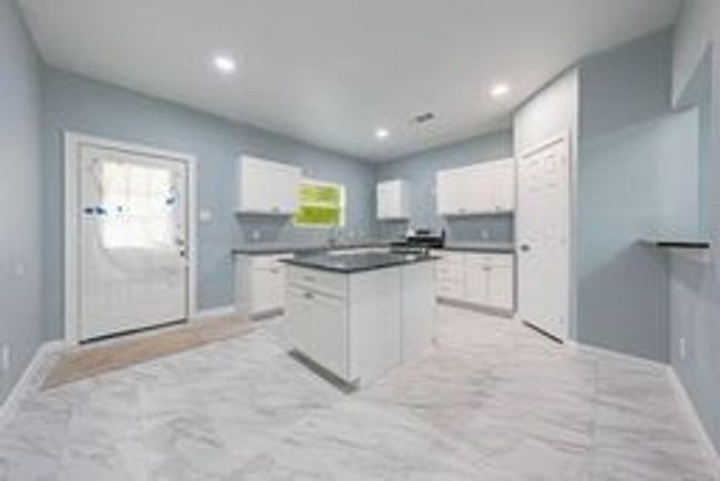 Kitchen with white cabinets, a kitchen island, dark countertops, and recessed lighting | Image 17