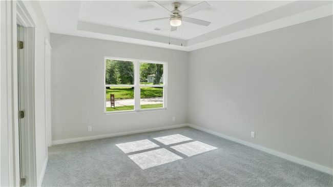 Carpeted empty room featuring a ceiling fan, baseboards, and a tray ceiling | Image 9