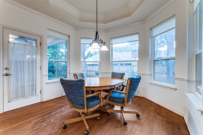 Breakfast room with a raised breakfast bar, Bay Window, Dining space with a raised ceiling, wood floors, ornamental molding, and baseboards | Image 10
