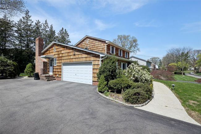 View of side of home with a lawn, a chimney, aphalt driveway, and a garage | Image 36