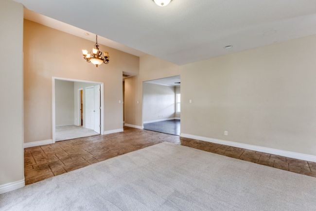 Carpeted spare room featuring stone finish flooring, baseboards, and a notable chandelier | Image 7
