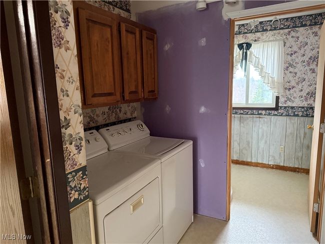 Laundry area with wallpapered walls, cabinet space, baseboards, and washer and dryer | Image 32