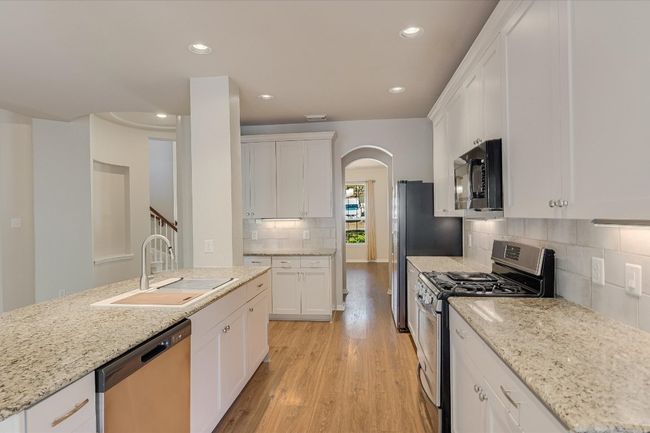 Kitchen with stainless steel appliances, light wood-style floors, recessed lighting, backsplash, and white cabinetry | Image 6
