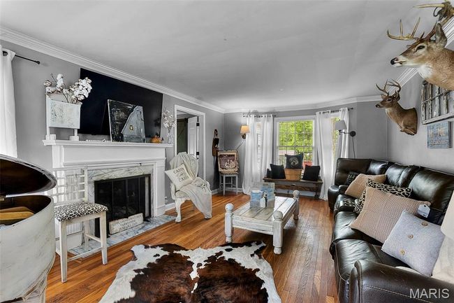 Living room with wood-type flooring, crown molding, and a fireplace | Image 4