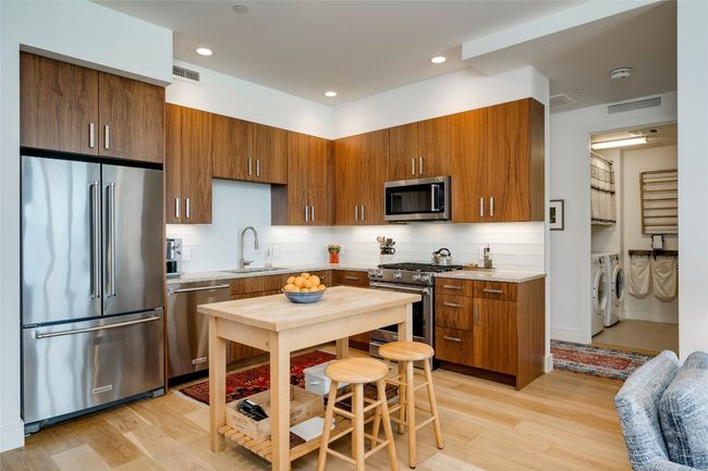 Kitchen with appliances with stainless steel finishes, washing machine and clothes dryer, light wood finished floors, light countertops, and recessed lighting | Image 9