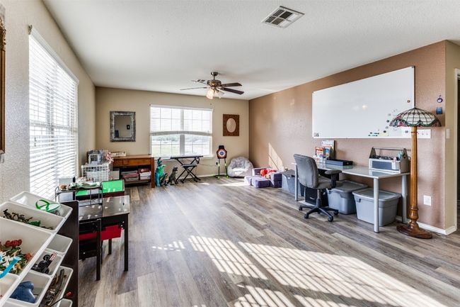 Office with wood finished floors, a ceiling fan, a textured wall, and baseboards | Image 18