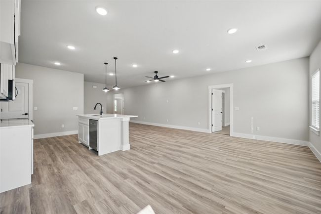Kitchen featuring light countertops, a sink, a center island with sink, open floor plan, and light wood-style floors | Image 5