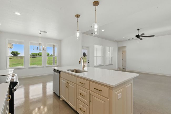 Kitchen featuring dishwasher, a sink, range, concrete floors, and baseboards | Image 8