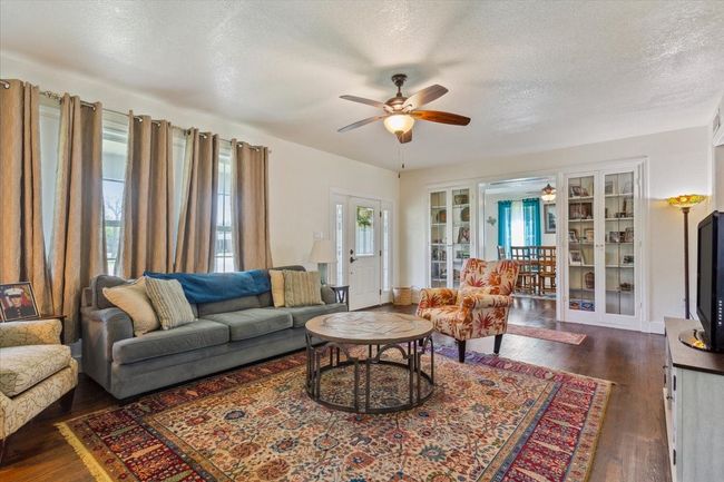 Living room featuring a textured ceiling, dark wood finished floors, and a ceiling fan | Image 8